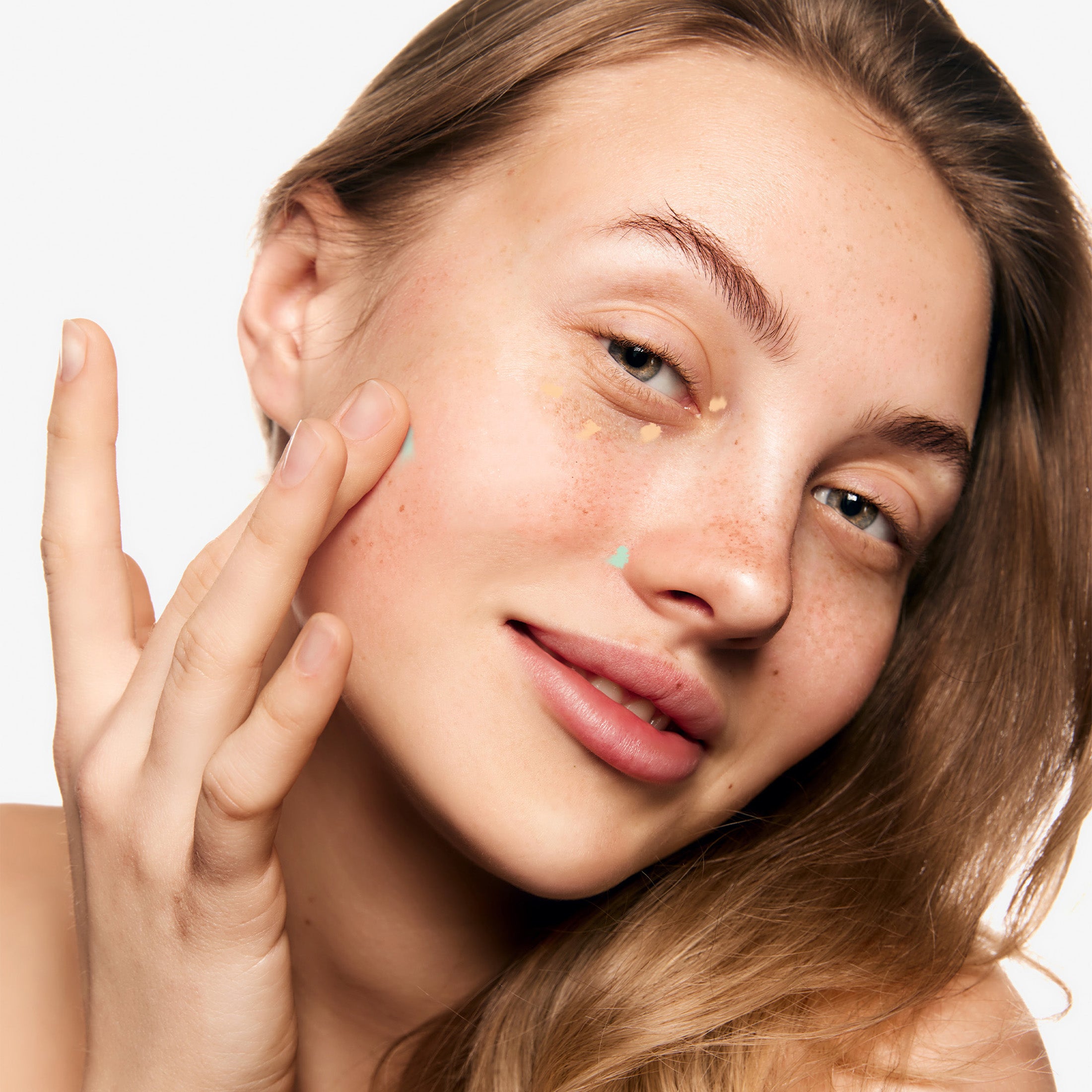 Color corrector applied to targeted areas to balance skin tone before full-coverage concealer application.
