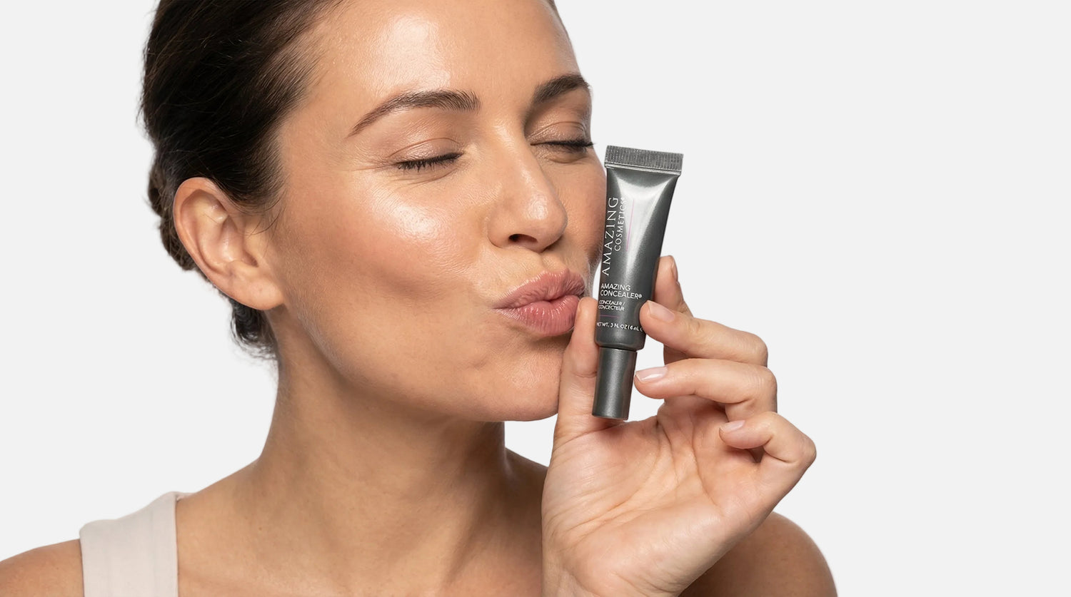 Woman holding a makeup product near her face on a white background